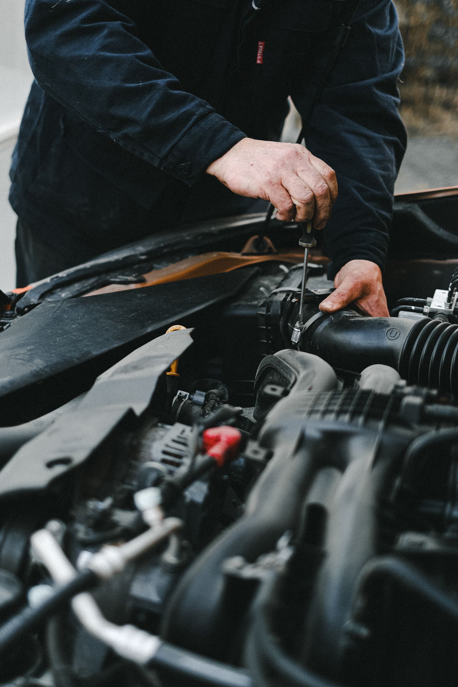Representative close-up of a mechanic working beneath an open vehicle hood
